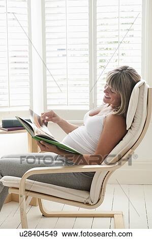 Pregnant woman sitting on chair with book View Large Photo Image Stock Photo - Pregnant woman sitting on chair with book. Fotosearch
