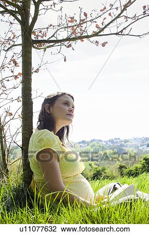 Pregnant woman sitting on grass View Large Photo Image Stock Image - Pregnant woman sitting on grass. Fotosearch