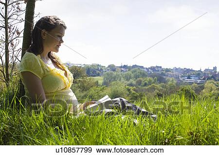 Pregnant woman sitting on grass View Large Photo Image Stock Photo - Pregnant woman sitting on grass. Fotosearch