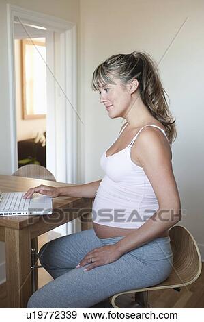 Stock Photo - Pregnant woman using laptop at home. Fotosearch