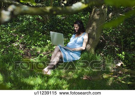Pregnant woman using laptop in woods View Large Photo Image Stock Photography - Pregnant woman using laptop in woods. Fotosearch