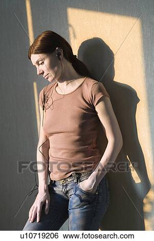 Redhead stands with hand in pocket listening to headphones View Large Photo Image Stock Photograph - Redhead stands with hand in pocket listening to headphones. Fotosearch
