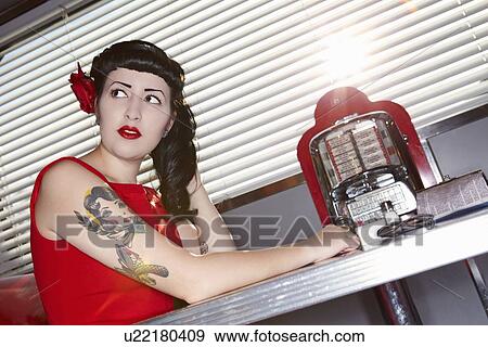 Stock Photo - Retro woman in red dress in American diner. Fotosearch