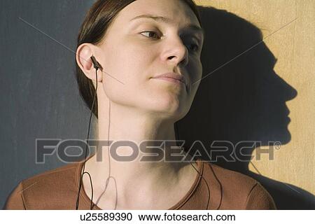 Stock Image - Shadow of redhead listening to headphones. Fotosearch