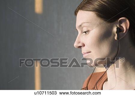 Stock Image - Side profile of redhead listening to headphones. Fotosearch