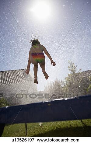 Stock Photo - South Africa Cape Town girl jumping on trampoline. Fotosearch