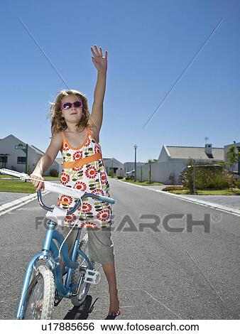 Stock Photograph - South Africa Cape Town girl standing on street with bicycle and waving. Fotosearch