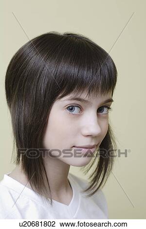 Stock Image - Studio portrait of girl with brown hair smiling. Fotosearch