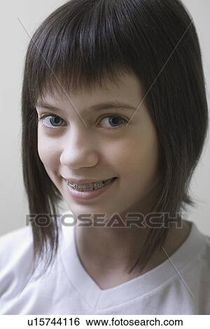 Stock Photograph - Studio portrait of girl with brown hair smiling. Fotosearch