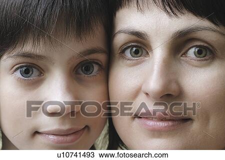 Stock Image - Studio portrait of mother and daughter smiling. Fotosearch