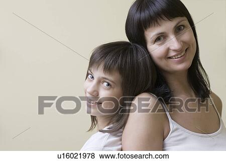 Stock Photo - Studio portrait of mother and daughter smiling. Fotosearch