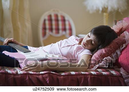 Stock Photo - Teenage girl asleep holding electric guitar. Fotosearch