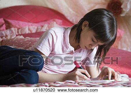 Teenage girl lying on bed doing homework View Large Photo Image Stock Image - Teenage girl lying on bed doing homework. Fotosearch