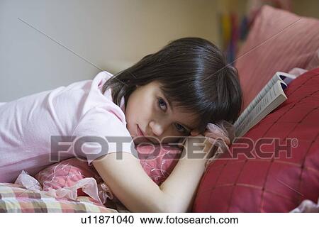 Stock Image - Teenage girl lying on bed. Fotosearch