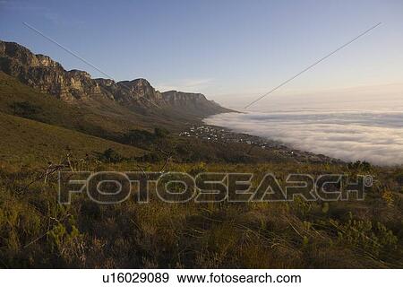 Stock Photo - The 12 Apostles of Table Mountain tower above Camps Bay and Bakoven. Fotosearch