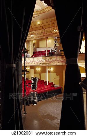 Stock Image - Theatre view through stage curtain. Fotosearch