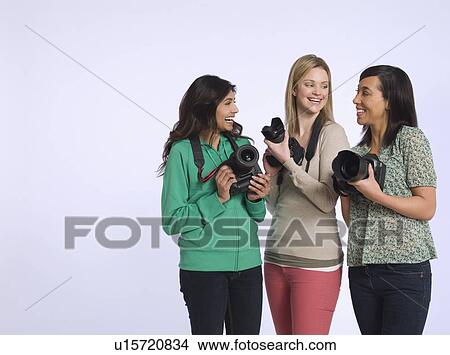 Three young women holding digital cameras studio shot View Large Photo Image Picture - Three young women holding digital cameras studio shot. Fotosearch