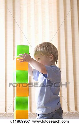 Stock Photo - Toddler builds with multi-coloured bricks. Fotosearch