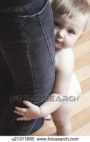 Stock Photography - Todller holds onto mothers legs first steps. Fotosearch
