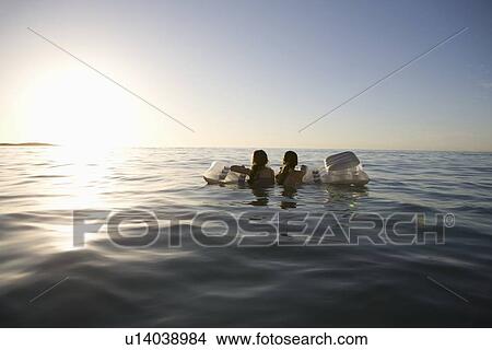 Twin sisters paddle out to sea on air bed View Large Photo Image Picture - Twin sisters paddle out to sea on air bed. Fotosearch