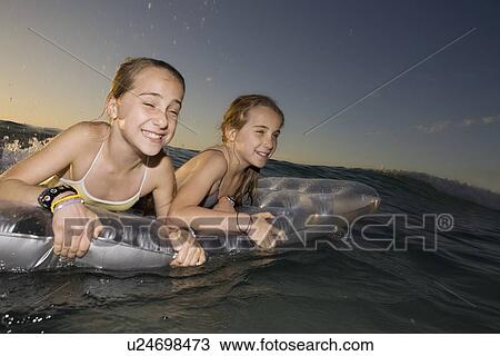 Twin sisters wave surfing on airbed View Large Photo Image Stock Image - Twin sisters wave surfing on airbed. Fotosearch