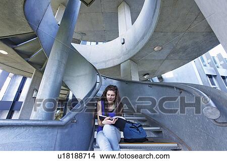 Picture - University student reading on staircase. Fotosearch