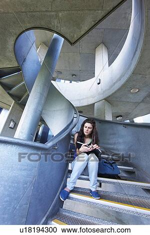 Stock Image - University student reading on staircase. Fotosearch