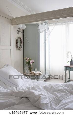 Unmade bed in sunlit beamed room View Large Photo Image Stock Photo - Unmade bed in sunlit beamed room. Fotosearch