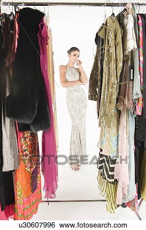 Stock Photograph - View through clothing rail of woman in long evening dress. Fotosearch