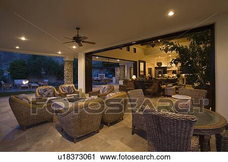 Stock Image - Wicker furniture in lit Palm Springs home. Fotosearch