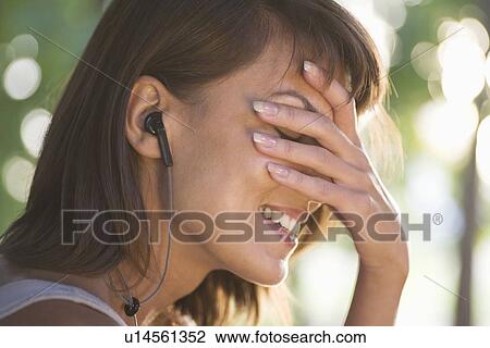 Woman covers her face laughing with headphones on View Large Photo Image Stock Image - Woman covers her face laughing with headphones on. Fotosearch