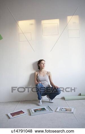 Woman decides on pictures to mount in new apartment View Large Photo Image Stock Photo - Woman decides on pictures to mount in new apartment. Fotosearch