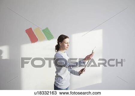 Woman deciding on paint sample in new apartment View Large Photo Image Stock Image - Woman deciding on paint sample in new apartment. Fotosearch