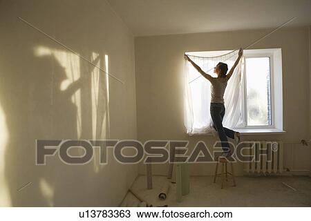 Woman fitting curtains in new apartment View Large Photo Image Stock Image - Woman fitting curtains in new apartment. Fotosearch