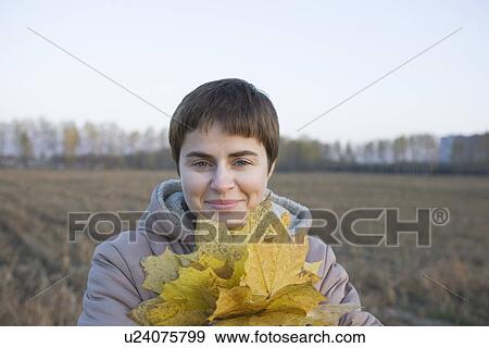 Woman holding leaves in field portrait View Large Photo Image Stock Photo - Woman holding leaves in field portrait. Fotosearch