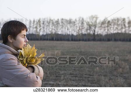 Woman holding leaves in field View Large Photo Image Stock Photo - Woman holding leaves in field. Fotosearch