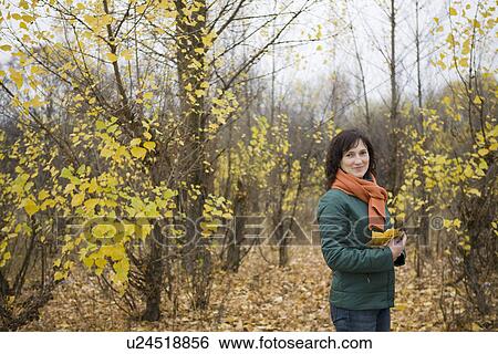 Stock Photograph - Woman holding leaves in forest portrait. Fotosearch