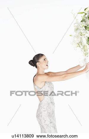 Stock Photo - Woman in evening dress accepts a bouquet of white flowers. Fotosearch