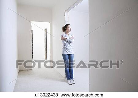 Stock Photo - Woman leans on archway of new apartment. Fotosearch