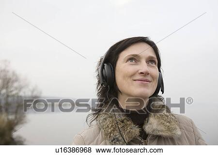 Stock Photo - Woman listening to music near lake. Fotosearch