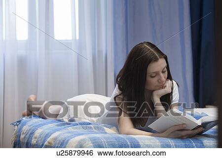 Woman lying on bed and reading book View Large Photo Image Stock Photograph - Woman lying on bed and reading book. Fotosearch