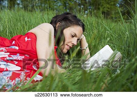 Woman lying on grass reading View Large Photo Image Stock Image - Woman lying on grass reading. Fotosearch