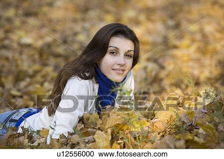Woman lying on leaves in park View Large Photo Image Stock Image - Woman lying on leaves in park. Fotosearch