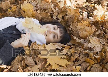 Woman lying on leaves in park View Large Photo Image Stock Photo - Woman lying on leaves in park. Fotosearch