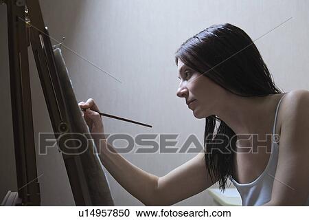 Stock Image - Woman painting on easel. Fotosearch