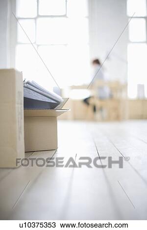 Stock Image - Woman sits at desk in window area of loft apartment. Fotosearch