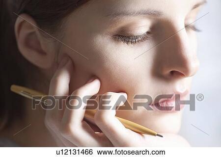 Woman sits holding pencil and leaning on chin View Large Photo Image Stock Photograph - Woman sits holding pencil and leaning on chin. Fotosearch