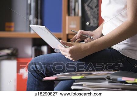 Stock Photo - Woman sits working on desk working on laptop. Fotosearch