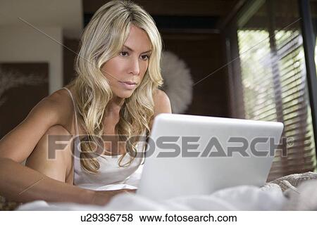 Woman sits working on laptop in home interior View Large Photo Image Stock Photo - Woman sits working on laptop in home interior. Fotosearch
