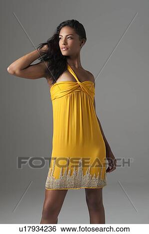 Stock Photograph - Woman stands in bright yellow dress. Fotosearch